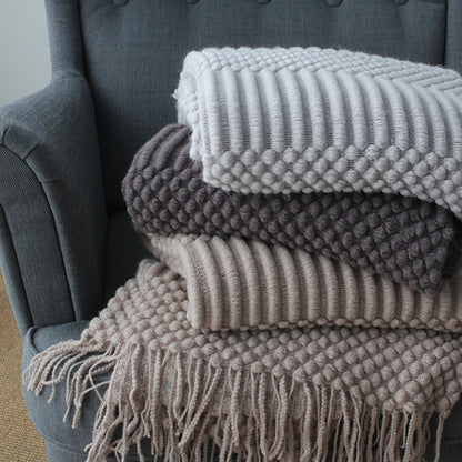 Stack of textured blankets on a gray armchair
