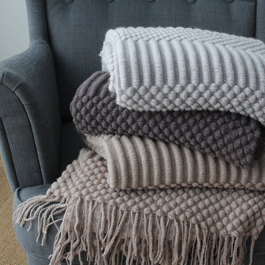 Stack of textured blankets on a gray armchair