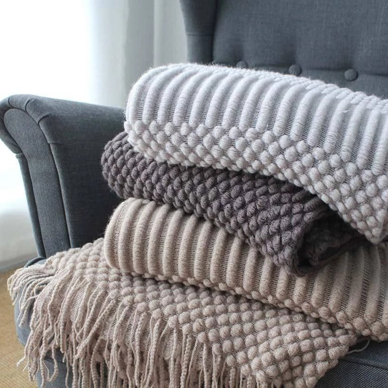 Stack of textured blankets on a gray armchair